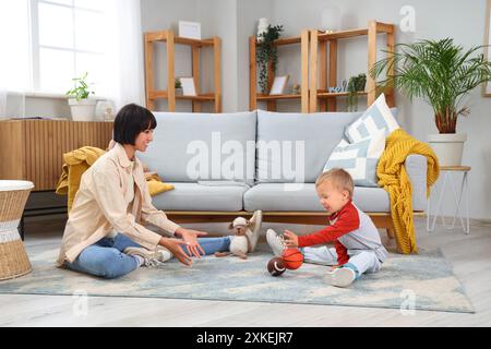 Die junge Mutter und ihr kleiner Sohn spielen zu Hause mit Bällen Stockfoto