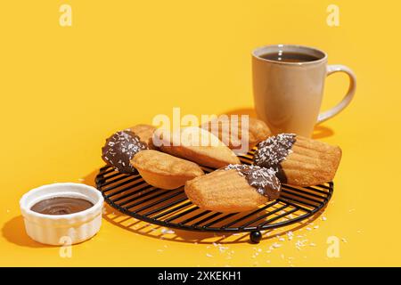 Raster mit köstlichen Madeleinen und Schüssel Schokoladenpaste auf gelbem Hintergrund Stockfoto