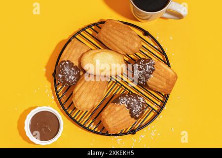 Raster mit köstlichen Madeleinen und Schüssel Schokoladenpaste auf gelbem Hintergrund Stockfoto