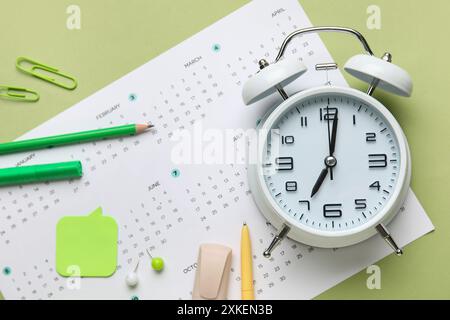 Kalender mit Wecker und Büropapier auf grünem Hintergrund Stockfoto