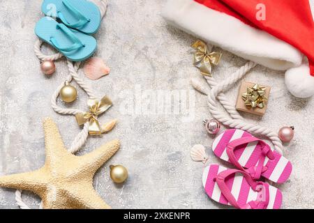 Flipflops für Kinder, Weihnachtsmann-Hut, Seil und Seesterne mit Weihnachtsdekoration auf weißem Grunge-Hintergrund. Draufsicht Stockfoto