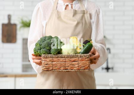 Schwangere Frau, die in der Küche Korb mit unterschiedlichem frischem Gemüse hält Stockfoto