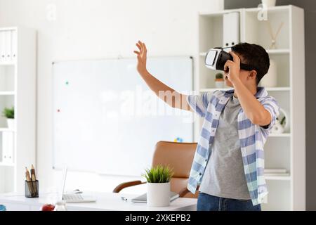 Kleiner Schuljunge mit VR-Brille im Klassenzimmer Stockfoto