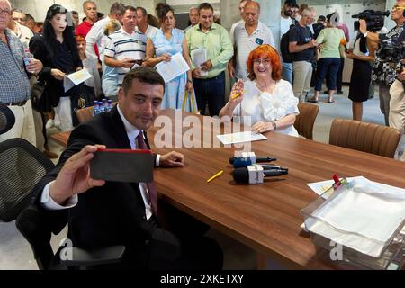 Bukarest, Rumänien. Juli 2024: George Simion (L), der Kandidat der rechtspopulistischen und nationalistischen Partei AUR (Alliance for the Union of Romanians), macht ein Selfie mit einer Frau, nachdem sie während einer Präsidentschaftskampagne in seinem Wahlkampfsitz im Bukarest Store den „Einschreibevertrag im Simion-Plan“ unterzeichnet hatte. Der "Simion-Plan" zielt darauf ab, den zinsfreien Kauf einer Wohnung ab 35.000 Euro und die Refinanzierung bestehender Hypothekarkredite zwischen 35.000 und 70.000 Euro zu erleichtern, ohne dass Zinsen und andere Kosten vollständig vom Staat subventioniert werden. Stockfoto