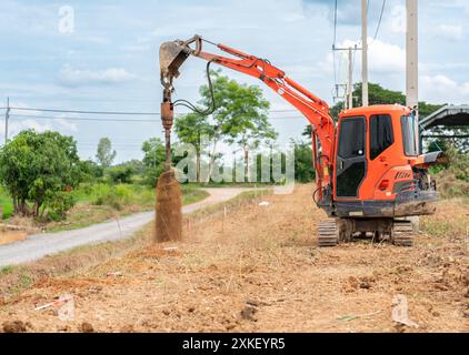 Minibagger macht Löcher mit Schneckenbohrer für die Installation von Stangenzaun auf der Baustelle. Stockfoto