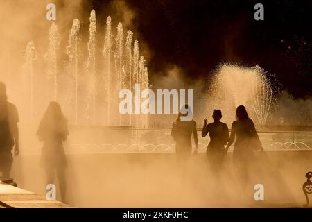 Bukarest, Rumänien. 22. Juli 2024: Menschen laufen an einem sehr heißen Tag durch den feinen Sprühnebel eines Brunnens. Quelle: Lucian Alecu/Alamy Live News Stockfoto