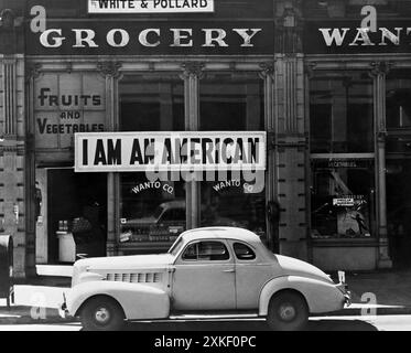 Oakland, Kalifornien, März 1942 Ein großes Schild mit der Aufschrift „I am an American“, das am 8. Dezember, einen Tag nach Pearl Harbor, in einem Geschäft in der 8. Und Franklin Street angebracht wurde. Das Geschäft wurde geschlossen, nachdem Personen japanischer Abstammung befohlen hatten, aus bestimmten Gebieten der Westküste zu evakuieren. Der Besitzer, ein Absolvent der University of California, wird während des Krieges mit Hunderten Evakuierten in den Kriegsumsiedlungsbehörden untergebracht sein. Stockfoto