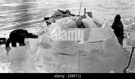 Hudson Bay, Kanada ca. 1930 Joe Apatok, Coppermine River Eskimo, baut Anfang des Winters sein neues Haus in der Nähe von Churchill. Das Iglu hat einen Durchmesser von 12 Fuß und ist komplett aus Eisblöcken gebaut und mit Schnee bedeckt. Hier wohnen Joe, seine Frau, zwei Kinder und sechs Schlittenhunde. Stockfoto