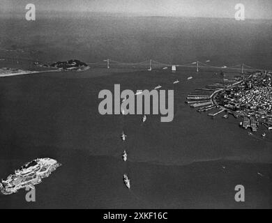 San Francisco, Kalifornien 28. Mai 1937 nachdem die Schiffe der United States Pacific Fleet in einer einzigen Datei unter der Golden Gate Bridge vorbeigefahren waren, dampften sie in die San Francisco Bay, um dort die Eröffnung der Golden Gate Bridge zu feiern. Dieses Bild zeigt die Schiffe in der Bucht, mit der San Francisco/Oakland Bay Bridge im Hintergrund und Alcatraz Island, dem Gefängnis der Vereinigten Staaten, im Vordergrund. Stockfoto