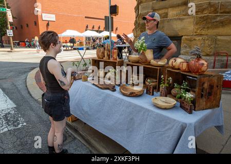 Eine Frau steht hinter einem Verkaufsstand, der Holzschüsseln und Vasen zum Verkauf auf dem YLNI Farmers Market im Zentrum von Fort Wayne, Indiana, USA, präsentiert. Stockfoto