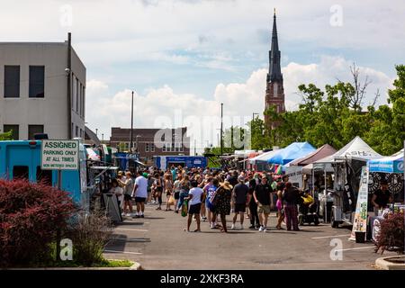 St. Paul's Lutheran Church erhebt sich über die Kunden, die eine Reihe von Verkaufsständen auf dem YLNI Famers Market im Zentrum von Fort Wayne, Indiana, USA, besuchen. Stockfoto