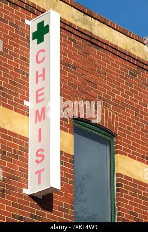 Ein vertikales Bild eines Schilds für eine Apotheke/Apotheke, das an einem roten Backsteingebäude an der Rokeby Road in Subiaco, Perth, Western Australia, angebracht ist. Stockfoto