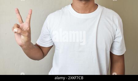 Ein Mann trug ein weißes T-Shirt und hielt den Zeigefinger hoch, während er zwei zählte Stockfoto