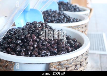 Schneidet schwarze Oliven mit einem Löffel in einer Schüssel, Stockfoto