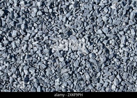 Graue, kleine Steine, Bodenstruktur. Schwarzer kleiner Straßenstein Hintergrund. Kieselstein. Dunkler Hintergrund von zerstoßenem Granitkies Stockfoto