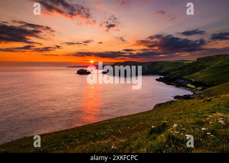 Lange Exposition des Sonnenaufgangs bei Sonnenaufgang in der Nähe der Sommersonnenwende, die über der Gullastem-Bucht aufgeht, aufgenommen von Barras Nose, Tintagel, Cornwall, Großbritannien Stockfoto