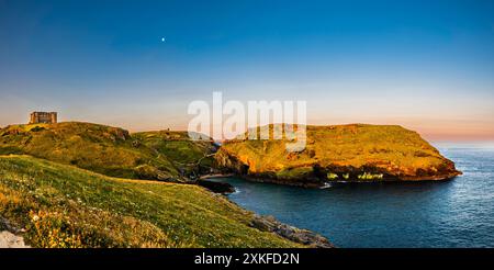 Sonnenaufgangslicht in der Nähe der Sommersonnenwende, die über Tintagel Haven and Island, Tintagel, Cornwall, Großbritannien, leuchtet Stockfoto