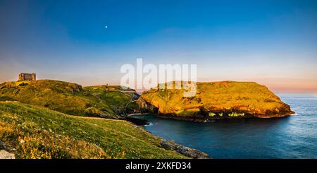 Lange Exposition des Sonnenaufgangs in der Nähe der Sommersonnenwende, glühend über Tintagel Haven and Island, Tintagel, Cornwall, Großbritannien Stockfoto