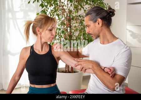 Professionelle Physiotherapeutin, die eine manuelle Schulterbeurteilung an einer Patientin durchführt Stockfoto