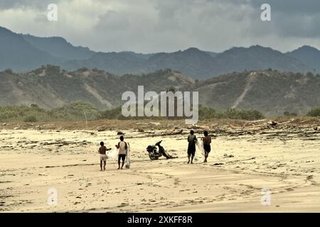 Fischer, die Fischernetze tragen, gehen am Kalala-Strand in Wula, Wula Waijelu, East Sumba, East Nusa Tenggara, Indonesien. Stockfoto