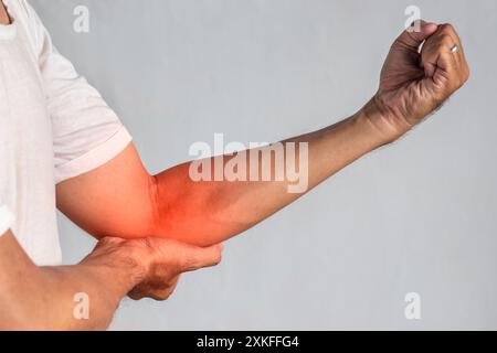 Schmerzen im Ellenbogengelenk eines südostasiatischen jungen Mannes. Konzept von Ellenbogenschmerzen, Verletzungen, Rheuma oder Arthrose. Stockfoto