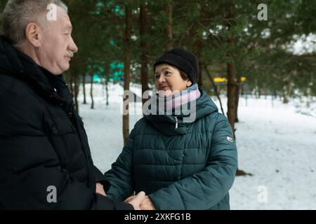 Niedliches, reifes Paar, das im Winter beim Spaziergang im Park Liebe für einander erlebt Stockfoto