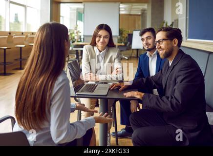 Mitarbeiter des Unternehmens, die sich auf Geschäftstreffen unterhalten, sitzen am Arbeitsplatz in einem modernen Büro. Stockfoto