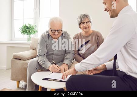 Immobilienmakler hilft glücklichem Seniorenpaar, Immobilienkaufvertrag zu unterzeichnen. Vertragsunterzeichnungsprozess positive und befähigende Erfahrung Stockfoto