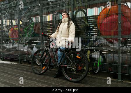 Frau steht neben zwei Fahrrädern vor dem Zaun Stockfoto