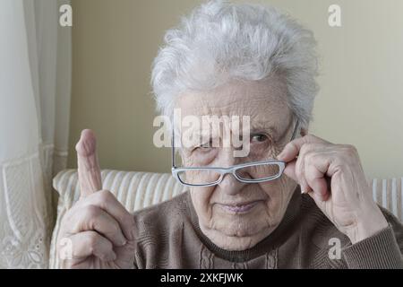 Eine ernste Seniorin mit dem Finger nach oben zur Mahnung/Warnung Stockfoto