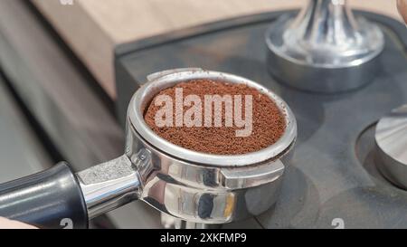 Nahaufnahme von frisch gemahlenem Kaffee in einem Portafilter, vorbereitet und bereit zum Tampfen, um einen perfekten Espresso zu erhalten. Stockfoto