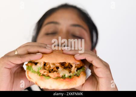 Frau, die gerade einen großen Hähnchenburger essen will, mit geschlossenen Augen. Stockfoto