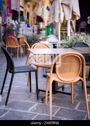 Leere Cafétische und -Stühle im Freien in einer bezaubernden europäischen Straßenlage schaffen ein entspanntes und einladendes Ambiente für Besucher. Stockfoto