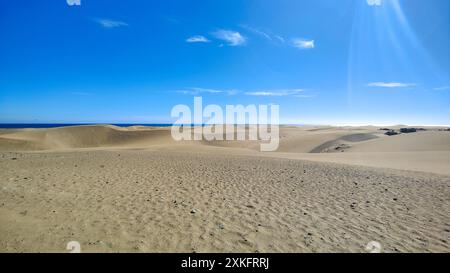 Eine ruhige Sandwüste unter blauem Himmel an einem warmen, sonnigen Tag, die Ruhe und Frieden beschwört Stockfoto