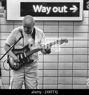 Ein Straßenfahrer, der in der Londoner U-Bahn auf einem Ausweg-Schild auftritt Stockfoto