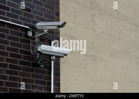 Zwei Überwachungskameras sind übereinander an einer Ziegelwand montiert. Die Kameras zeigen nach außen und erfassen die Umgebung. Stockfoto