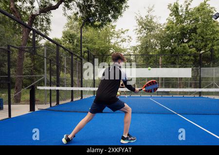 Junger Mann, der Padel-Tennis auf dem Platz im Freien spielt Stockfoto