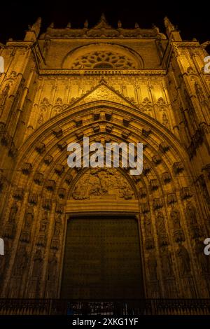 Tür der Himmelfahrt (Spanisch: Puerta de la Asuncion) der Kathedrale von Sevilla bei Nacht in Spanien, Hauptportal der Westfassade, gotischer Revival-Archit Stockfoto