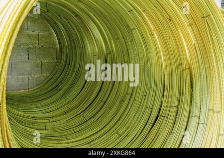 Gelbe Drähte zu Rolle mit sichtbaren Details verdreht. Abstrakter industrieller Hintergrund. Drahtstruktur Stockfoto