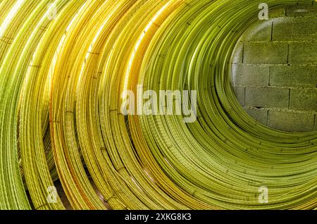 Gelbe Drähte zu Rolle mit sichtbaren Details verdreht. Abstrakter industrieller Hintergrund. Drahtstruktur Stockfoto