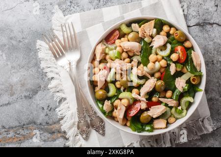 Köstlicher Kichererbsen Thunfisch Salat mit gesunden Zutaten wie frischem Gemüse und Kräutern aus der Nähe in einer Schüssel auf dem Tisch. Horizontale Draufsicht von oben Stockfoto