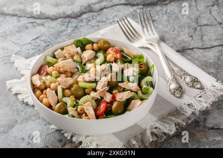 Köstlicher Kichererbsen Thunfisch Salat mit gesunden Zutaten wie frischem Gemüse und Kräutern aus der Nähe in einer Schüssel auf dem Tisch. Horizontal Stockfoto