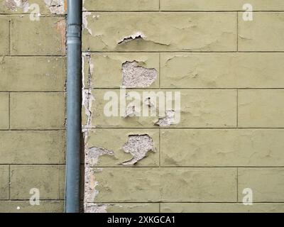 Hauswand mit einem Wasserschaden. Der Lack löst sich aufgrund der Feuchtigkeit ab. Das alte Gebäude hat ein verwittertes Äußeres und muss renoviert werden. Stockfoto