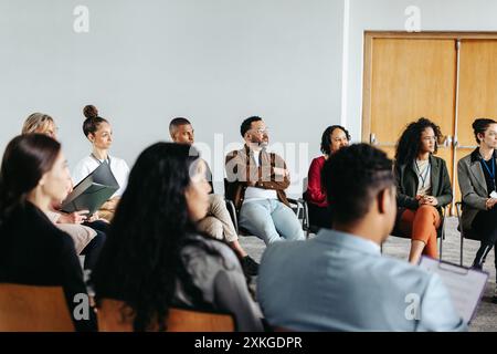 Eine vielfältige Gruppe von Fachleuten, die aufmerksam an einem Unternehmensworkshop teilnehmen, um Fähigkeiten und Zusammenarbeit zu verbessern. Stockfoto