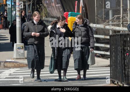 Klassenkameraden einer Pfarrschule für religiöse jüdische Mädchen gehen nach Hause, während sie ein animiertes Gespräch führen. An der Bedford Avenue in Williamsburg, NYC. Stockfoto