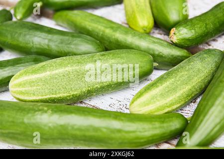 Ein Nahaufnahme-Bild mit frisch geernteten Gurken auf einem rustikalen Holztisch, die ihre leuchtende grüne Farbe und Textur hervorheben. Stockfoto