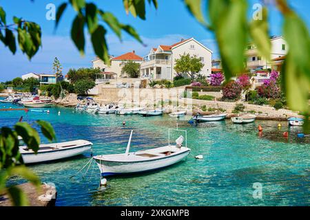 Kleine Motorboote schwimmen auf türkisfarbenem Wasser in der Nähe eines Steinpiers um Reihe von wunderschönen Häusern mit üppigen Gärten. Sommerurlaub an der Adria in Ro Stockfoto