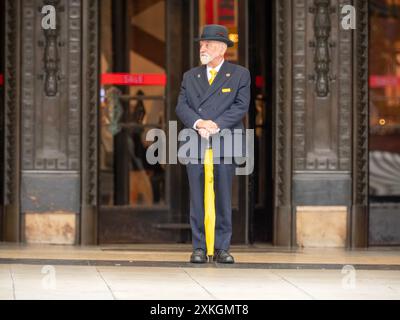 Uniformierter Türsteher begrüßt die Käufer vor Selfridges in der Oxford Street London Stockfoto