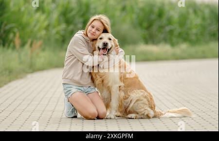 Das Mädchen Sitzt Mit Golden Retriever Auf Einem Morgenspaziergang Stockfoto