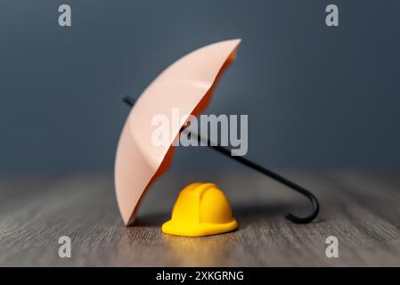Ein gelber Schutzhelm und Regenschirm. Arbeitnehmerversicherung, Sicherheit an erster Stelle. Stockfoto